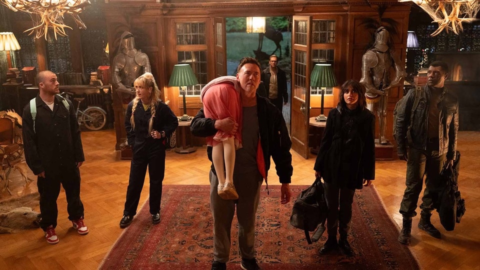 Peter (Kevin Durand) carries Abigail (Alisha Weir) while the cast stands next to him in Abigail (2024).